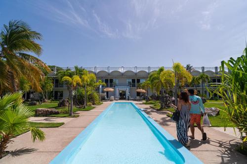two people standing near a swimming pool at a resort at Solace by the Sea in Ponce