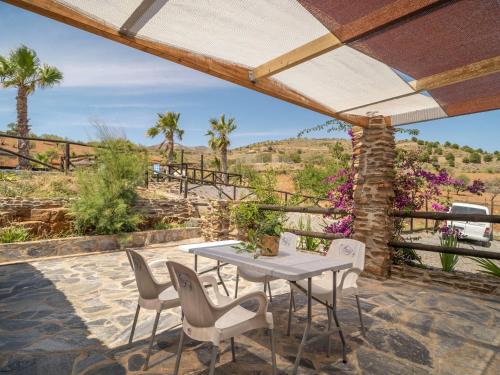 a patio with a table and chairs and palm trees at Rural House Adra near Beaches & Views in Las Hoyas del Barranco