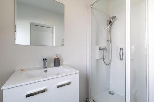 biała łazienka z umywalką i prysznicem w obiekcie Idéal couples & pro - Patio extérieur- Proche centre ville et gare - Promenade au bord de la Charente - Parking à proximité - Wifi très haut debit - Équipement premium -Netflix w mieście Angoulême