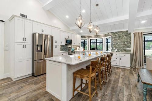 a kitchen with white cabinets and a large island with bar chairs at Tahiti Cottage in Marco Island