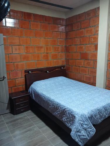 a bedroom with a bed and a brick wall at Casa Girardot in Tocaima
