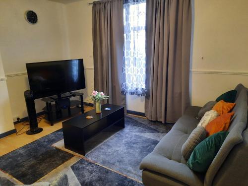 uma sala de estar com um sofá e uma televisão de ecrã plano em 47R Place em Dagenham