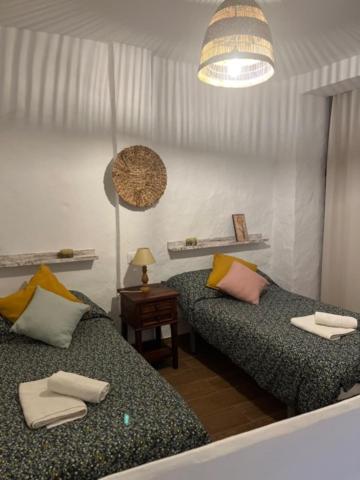 Habitación con 2 camas y mesa con lámpara. en Casa Alondra, en El Gastor