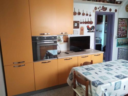 une cuisine avec des armoires jaunes, une cuisinière et une table dans l'établissement casa miglio, à Marina di Pietrasanta