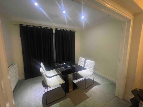 a dining room with a table and white chairs at Lovely Detached house in lovely location in West Drayton