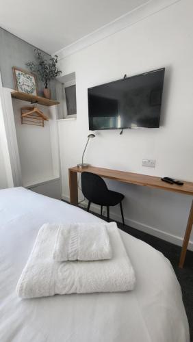 a bedroom with a bed with a desk and a television at The bolt in Newhaven