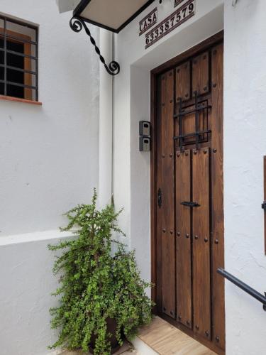 a wooden door on a white building with a plant at Apartamentos Mirador en la Plaza de Zahara in Zahara de la Sierra