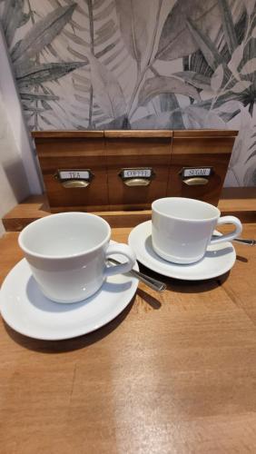 two white cups and saucers on a wooden table at The bolt in Newhaven
