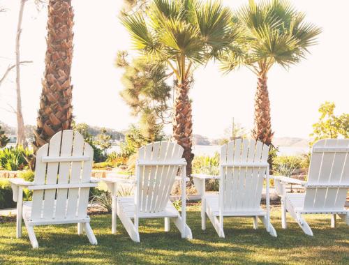 3 sillas blancas, una mesa y palmeras en Back Bay Inn, en San Luis Obispo