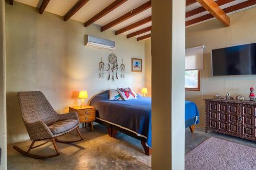 a bedroom with a bed and a chair and a tv at Marmot Hill Apartment, loft for 2, Las Pocitas in Máncora