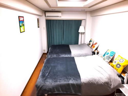 a small bedroom with a bed and a window at Shinjuku Harusame Apartment -Twin room- in Tokyo