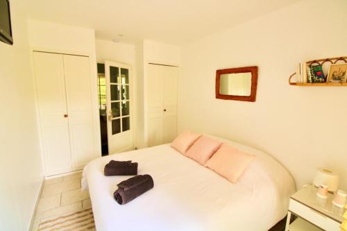 Un dormitorio con una cama blanca con dos bolsas. en Le 7 du Clos Fleuri, 