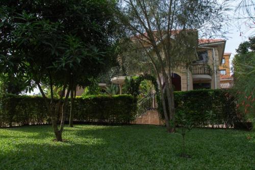 a house with trees in front of a yard at Villa Karibu in Kampala