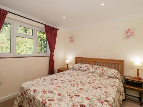 a bedroom with a bed and two windows at Lapwing Lodge in Cullompton