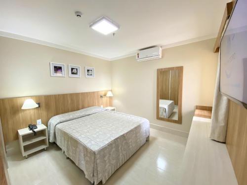 een hotelkamer met een bed en een spiegel bij PIAZZA DIROMA - ACQUA PARK, SPLASH e SLIDE in Caldas Novas