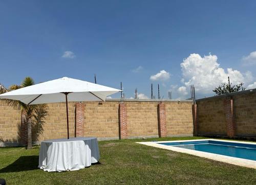 a table with an umbrella next to a swimming pool at Casa los ventanales in Chiconcuac