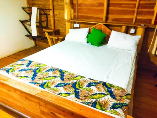 a bedroom with a bed with white sheets and green pillows at Yala Bay Holiday Resort in Tissamaharama