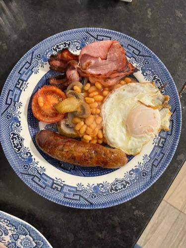 a blue and white plate of food with sausage beans and eggs at The Old Postie Bed & Breakfast in Annesley