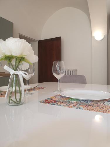 a table with a vase of flowers and two wine glasses at Grisella Grace Home in Casale Monferrato