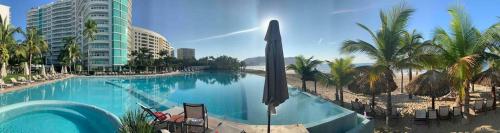 - une piscine à côté d'une plage bordée de palmiers et d'un bâtiment dans l'établissement Bay View Marina- Monthly rentals special at Tripintravel, à Ixtapa