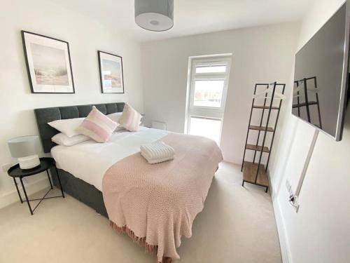 a white bedroom with a large bed with pink pillows at Stunning 2 bed, water front Poole Quay Apartment. in Hamworthy