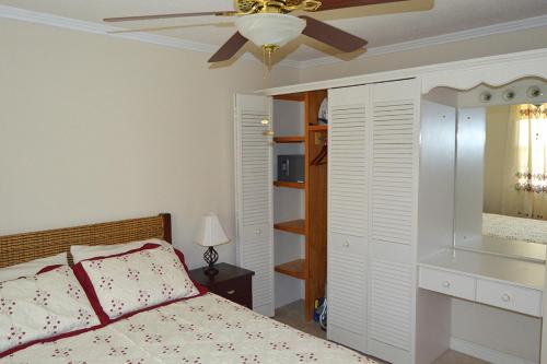 Un dormitorio con una cama y un ventilador de techo. en Ocean Path Villas, en Christ Church