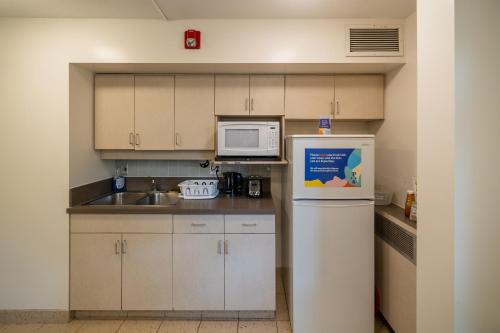 a small kitchen with a refrigerator and a microwave at Pacific Spirit Hostel in Vancouver