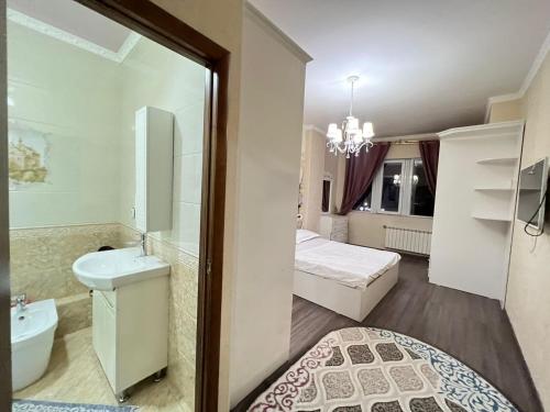 ein Bad mit einem Waschbecken, einem WC und einem Bett in der Unterkunft ЖК Биик in Schymkent