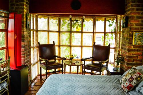a bedroom with two chairs and a table in front of a window at Tu Casa - Hotel Rural in Sopó