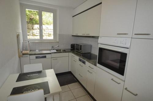 uma cozinha com armários brancos e um forno com placa de fogão em Casa Carmela em Solothurn