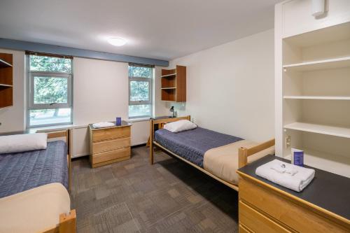 a bedroom with two beds and a desk and shelves at Pacific Spirit Hostel in Vancouver