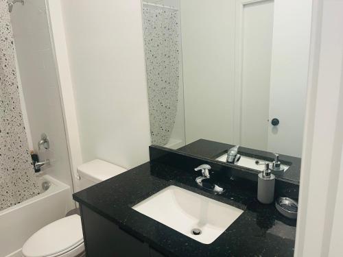 a bathroom with a sink and a toilet and a mirror at Brand New Townhouse, min from Disney in Kissimmee