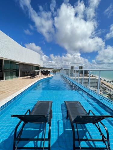 a swimming pool on the roof of a building with chairs at RN Studio Maceió Apto 302 in Maceió