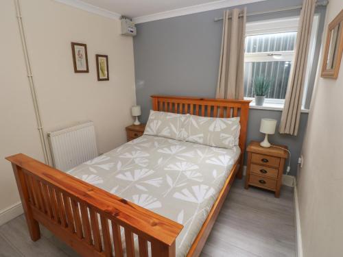 ein kleines Schlafzimmer mit einem Bett und einem Fenster in der Unterkunft Barn Cottage in Laugharne