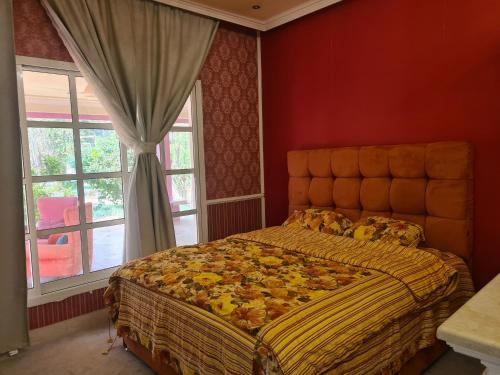 ein Schlafzimmer mit einem großen Bett in einem roten Zimmer in der Unterkunft Botanical Garden Vacation House in Liwa