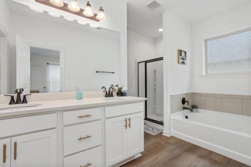 a white bathroom with two sinks and a bath tub at Luxury Townhome by LSU campus in Baton Rouge