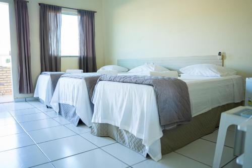 a group of three beds in a hotel room at Pousada Aeroporto in Parnaíba