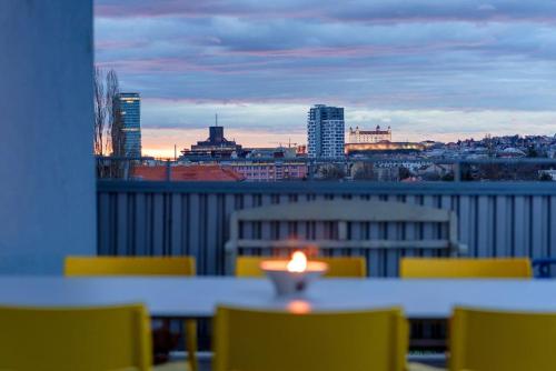 una mesa con sillas amarillas y vistas a la ciudad en Tranquil designer apartment with 40m2 terrace overlooking Castle of Bratislava, en Bratislava