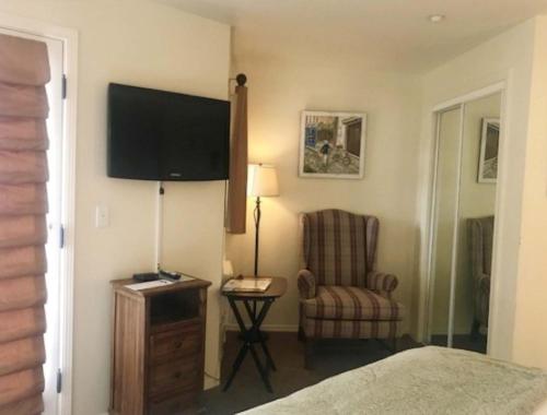 a bedroom with a bed and a chair and a television at Back Bay Inn in San Luis Obispo