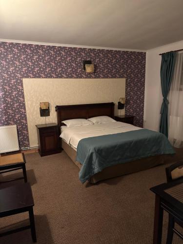 um quarto com uma cama grande e papel de parede roxo em Pensiunea Casa Albă em Ghimbav