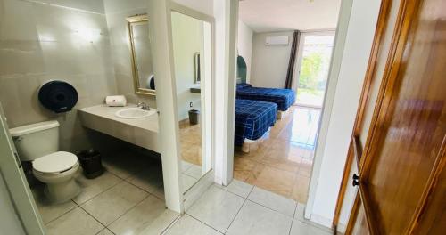 a bathroom with a toilet and a sink and a bed at Hotel La Cascada in Aguascalientes