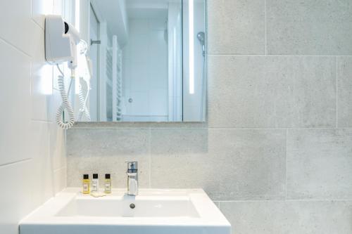 um lavatório de casa de banho com um espelho e um telefone em La Mère Poulard em Monte Saint-Michel