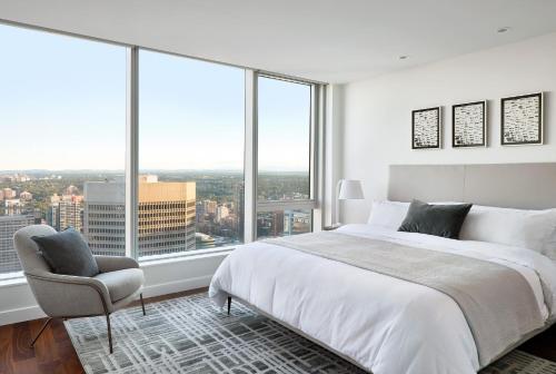 a bedroom with a bed and a chair and large windows at Award winning 1 bedroom apartment - extended stay in Calgary
