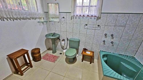 y baño con aseo verde y bañera. en Riacho Doce Pousada, en São Francisco Xavier