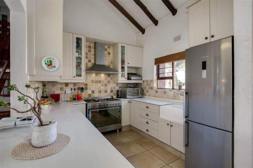 uma cozinha com armários brancos e um frigorífico de aço inoxidável em Paulshof Sandton Apartments - Monchique em Sandown