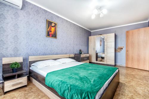 ein Schlafzimmer mit einem großen Bett und einer grünen Decke in der Unterkunft Квартира в престижном районе в новостройке in Pawlodar