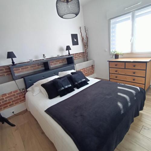 a bedroom with a large bed with black blankets and pillows at L'écurie d'antan in Hautot-Saint-Sulpice