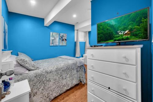 a bedroom with a bed and a tv on a blue wall at 52-3 Bed Suite On Lake Central Ac By Airport in Calgary