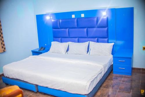 a blue bedroom with a large bed with a blue headboard at Ritz & Gold Hotel & Suites, Makurdi in Makurdu