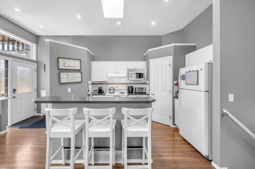 uma cozinha com electrodomésticos brancos e uma mesa com bancos em 12 Spacious Home W Ac, Crib, Garage, By Airport em Calgary
